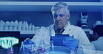 Mature lab scientist testing chemical reactions with a beaker and recording the data on a tablet in an ultraviolet lit lab. Doctor wearing protective gloves while experimenting in a research facility