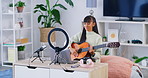 Female influencer recording a guitar tutorial for her music blog or live streaming channel at home. Young musician creating content and engaging with her viewers and subscribers during an online vlog