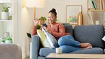 Woman online shopping with a phone and and credit card at home. Happy consumer entering her banking details to process a quick and secure internet payment while spending money on deals and bargains