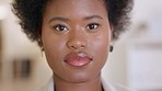 Sad young woman with serious facial expression looking ahead with concern in her eyes. Portrait of an unhappy stressed afro American female mother standing inside staring at the camera blinking