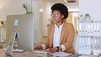 Young woman working on desktop computer and tablet, typing and writing her new business strategy ideas in a notebook. An African America female marketing executive and professional in a modern office