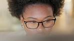 Closeup of a black business woman with glasses reading information on a computer screen while working in an office. One young entrepreneur thinking and carefully analyzing reports and plans online