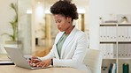 Portrait of a young business woman browsing on a laptop while working in an office. Ambitious and confident african entrepreneur smiling while doing research and planning online in a startup company