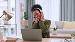 Young black woman wearing headphones and using a laptop in a home office. Happy African American female listening to a playlist while working remotely from a house. Lady streaming songs while working