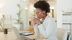 African businesswoman using laptop and drinking coffee while on a break and checking her email. Happy afro female entrepreneur feeling inspired and thinking of innovative ideas for her startup