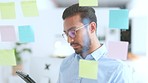 Young business man brainstorming and planning a marketing strategy on a glass wipe board at work. Happy male corporate professional smiling and nodding while thinking of ideas in the office boardroom