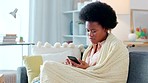 Sick woman texting her friends and loved ones on a phone while looking unhappy suffering from a cold or flu. One young and unhappy black female suffering from covid fatigue while browsing online
