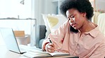 Female student making a phone call while typing an academic essay or doing a homework assignment alone at home. Young university or college student with afro getting help with drafting an email