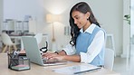 Young woman happily typing on laptop in neat white office doing business. Professional female is attractive and formal with work equipment and stationery around her. Busy emailing or messaging