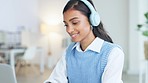 Trendy young business woman with headphones listening to music while working on a laptop. Modern creative digital intern enjoying an audio playlist to keep her motivated and inspired at her work