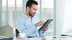 Confident manager or business owner browsing on a digital tablet online while sitting in a modern office. Successful startup entrepreneur smiling at his desk and checking emails looking happy