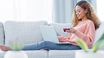 Happy adult woman excited online purchase experience. Female on sofa in a comfortable environment making payment on laptop. Girl providing banking information for purchased merchandise.