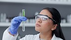 Medical research, serious female scientist analyzing liquid biochemical in test tube while working in a laboratory. Closeup up face of woman wearing gloves and goggles for safety while experimenting 