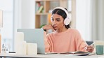 Student listening to music, researching on laptop and studying distance learning course in home living room. Woman wearing headphones for calming meditation song or binaural beats to help concentrate