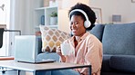 Woman laughing while watching funny series on a laptop at home. Happy female drinking coffee while enjoying a weekend of hilarious entertainment. Streaming comedy movies and sitcom shows online