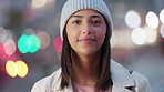 Portrait of laughing girl with bokeh lights in winter looking joyful. Cute and happy young woman smiling, enjoying a walk outside on a cold day in the city isolated against a blurred urban background