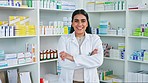 Portrait of female pharmacist in a pharmacy. One medical professional standing alone in drug store dispensary with many boxes of pills and tablets on shelves. Confident woman working with medication