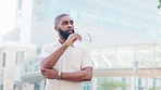 Young black man stand in the street and takes off his glasses thinking about his next business idea in architecture inspired by modern buildings around him. Portrait of handsome guy in the city