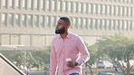 Handsome stylish businessman walking to work, holding a cup of coffee in the city. Young african american male entrepreneur commuting to his corporate job while looking confident in the morning 