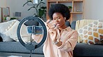 Afro beauty influencer, vlogger or podcast host talking, using phone to film live stream makeup tutorial with new mascara makeup. Excited woman using technology to promote cosmetic product from home