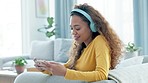 Woman using a phone and headphones to stream online, watch and cheer for favourite sports team. Happy gamer playing virtual game on technology with and celebrating winning victory in home living room