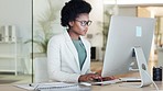 African female financial manager writing notes from her computer in her office. A black woman investment advisor working at her accounting firm. Accountant calculating company funds at the workplace