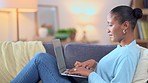 Adult woman working at home with laptop on sofa. Independent lady typing, engaging and creating documents adding online content. Girl laying on couch busy with work in a comfortable environment.