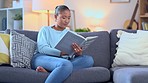 Young woman reading a book or novel or studying for exams at home while sitting and relaxing on the couch inside. Happy and beautiful female student seated on a sofa with a textbook or study material
