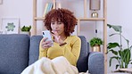 Happy carefree woman sending a text message on a phone, laughing and sitting on a couch at home. Young casual female scrolling and zooming while chatting online. Reading funny memes on social media