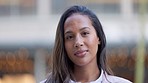 Closeup face of smiling volunteer worker with brown eyes looking forward with caring, friendly or kind facial expression towards humanity. Happy and sweet woman isolated against bokeh city background