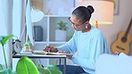 Market research analyst witing and taking notes in a diary while working remote at a desk at home. One young, serious black female researcher planning and organizing her online findings and results