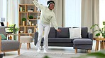 Woman dancing to her favorite songs while wearing headphones alone in the living room at home. Young, carefree and happy black female listening to music and having fun in the lounge of an apartment