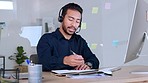 Male call centre agent talking on headset and writing in his note while working in an office. Confident salesman typing on computer and giving good news while working in customer service and support
