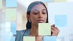 Market research concentrating while planning and writing ideas and results alone in an office at work. One creative and serious business woman brainstorming and writing reminders on sticky notes