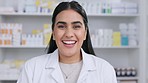 Happy smiling professional female pharmacist in pharmacy. Woman with big smile, laughing behind work counter. Product medication in the background of the store ready to be provided to patients.