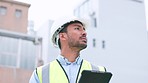 Construction worker holding a digital tablet while doing inspection. Organized male engineer or technician in a hardhat checking project plan with latest tech. Worker looking or overseeing operations