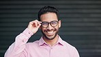 Happy, confident and relaxed young nerd man wearing glasses and smiling while looking into the camera. Portrait of laughing, proud and satisfied IT technician standing in front of office garage door