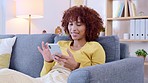 Happy, smiling and laughing woman texting, browsing and scrolling on phone at home. Cheerful female chatting on social media, typing online and watching funny internet memes while relaxing on a sofa