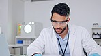 Serious young male scientist thinking and looking at data on paper in a laboratory. Portrait of a science researcher in front of a computer. Focused lab worker working on the success of a covid cure.