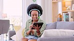 Happy, smiling and African woman browsing, streaming music and watching videos online on a tablet with headphones. Cheerful, joyful, and relaxed black female enjoying music while searching the web
