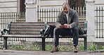 Serious, casual and relaxed man typing text on phone, browsing social media and checking notifications while sitting on a bench in a park. Male entrepreneur and guy reading and replying to emails