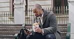 Young professional texting, browsing and typing on a phone while eating a meal on lunch break in a city. Hungry man reading social media, business news and updates before his morning commute to work