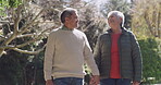Happy senior couple enjoying retirement outdoors in a green park or garden together. Healthy, in love and calm retired pensioner, man and woman walking holding hands with nature copy space background