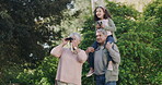 Happy, carefree and exploring with binoculars, grandparents carrying granddaughter on outdoor adventure. Young girl having fun with her grandfather and grandmother enjoying a weekend together outside