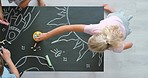 Fun, creative and educational group drawing for kids using chalk on a blackboard from above. Small children and friends getting creative and having fun with elementary lesson for art project