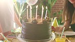 Kids birthday celebration with cake and blowing out candles. Enjoying a decorated party with baked chocolate dessert while making a wish on a candle. A festive occasion around a sweet confection