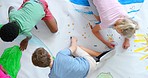 Children drawing, coloring and having fun on a colorful play mat from above. Small diverse kids and their friends on a white canvas, spending time at a preschool being creative during art class