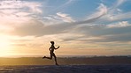 Fit, running and active athlete at sunset training, exercising and jogging along a sea at dusk. Silhouette of sporty, athletic and powerful woman in cardio, stamina and endurance workout by the ocean