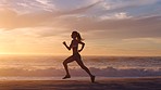 Active, fit and motivated woman running in slow motion on a beach at sunset outside. Silhouette of a determined and healthy female exercising and training outside near the ocean on a cloudy day.