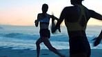 Fit, active and athletic women running, racing and competing on sunset or morning run on a beach. Sporty, healthy and energetic athletes working out, exercising and training near sea or ocean at dawn